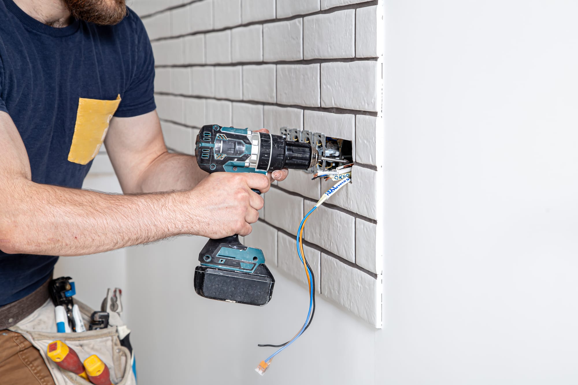 Électricien perçant un mur pour installer des prises électriques